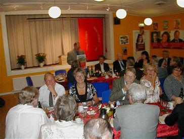 festdeltagere 23. oktober - Margrethe Bogner ved forreste bord i lys bluse  - Formanden viser vores jubilæumsplakat